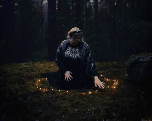 ninni-metsassa-keha woman sits in a forest in the middle of a light circle