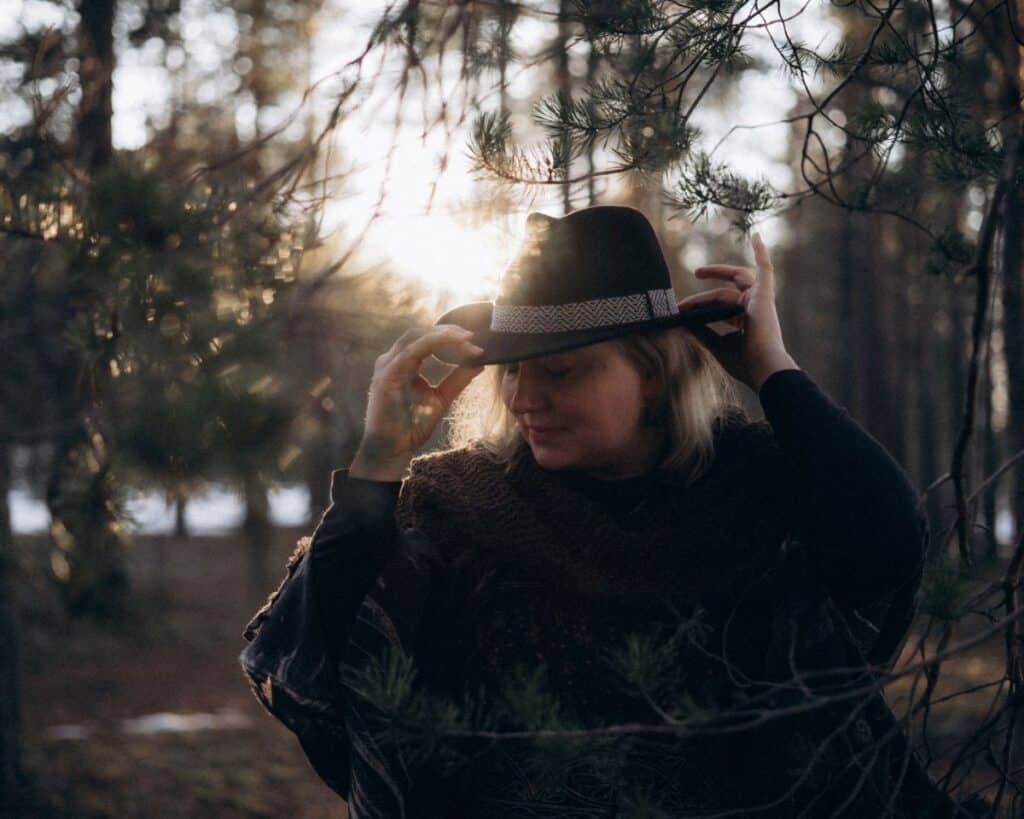 woman against sunset holindg her hat