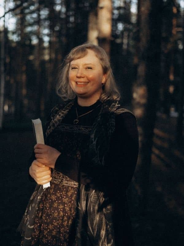 smiling woman in forest with a book